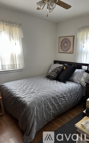 A bedroom with a bed, pillows, and a ceiling fan.