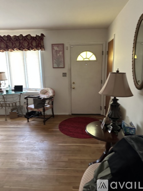 A living room with a chair, a table, a lamp, and a painting on the wall.