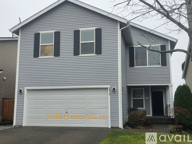 A grey house with a white garage door and a sign that says GMDI Enterprises Inc.