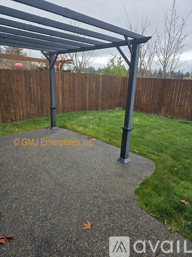 A grey metal pergola stands over a concrete walkway.