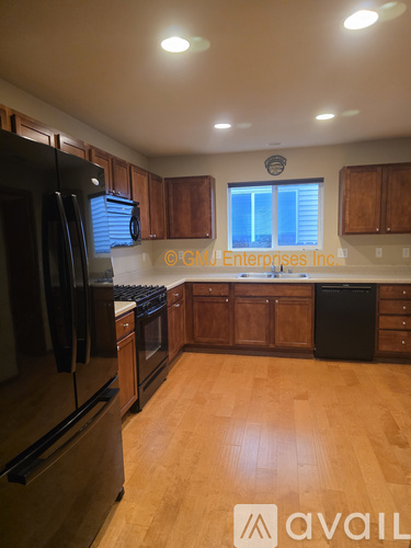 A kitchen with wooden cabinets and a black fridge.