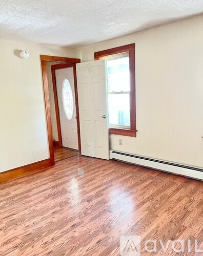 A room with wooden flooring and a door leading to another room.