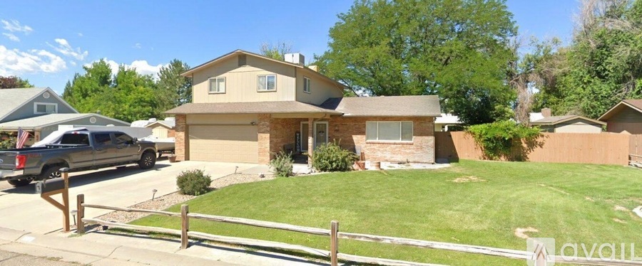 A house with a brown roof and a white fence in front of it.