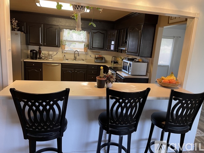 A kitchen with black chairs and a white counter.