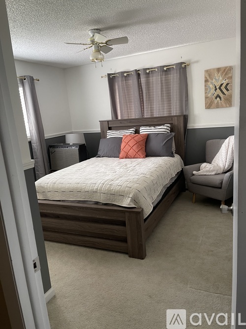 A bedroom with a bed, chair, and ceiling fan.