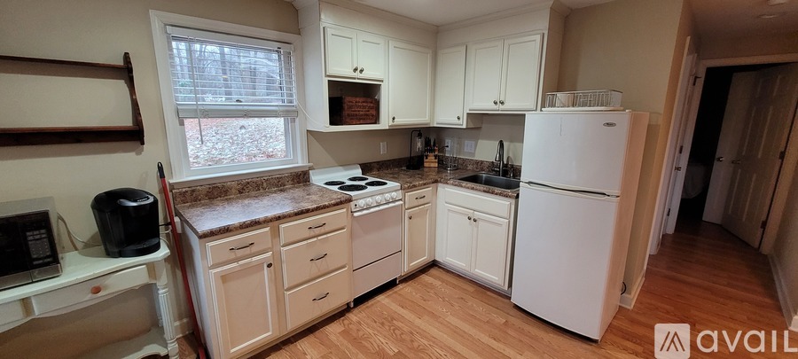 A kitchen with white appliances and wooden floors.