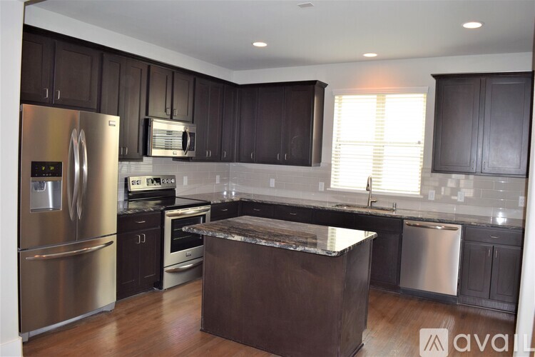 A modern kitchen with dark brown cabinets and stainless steel appliances.