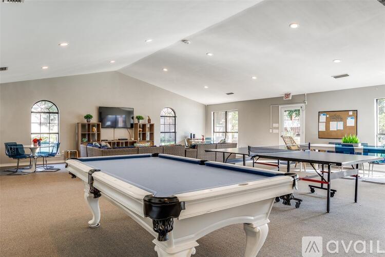 A pool table is in the middle of a room with a television and a chair.