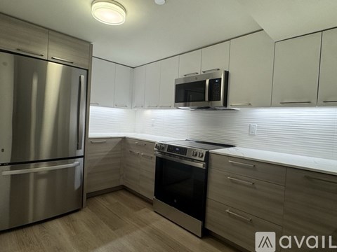 A modern kitchen with a stainless steel refrigerator and a microwave oven mounted above the stove.