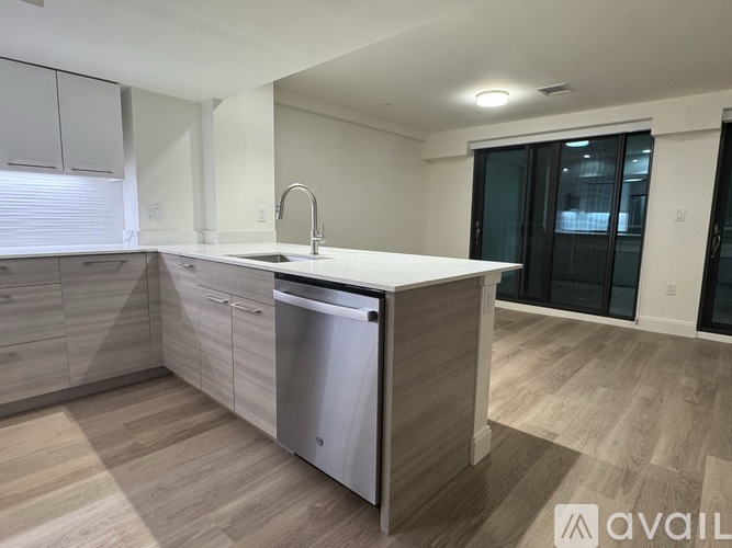 A modern kitchen with a stainless steel dishwasher and wooden flooring.