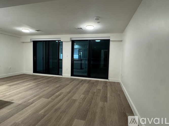 A room with wooden flooring and two glass doors.