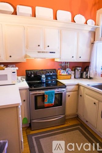 A kitchen with orange walls and white cabinets.