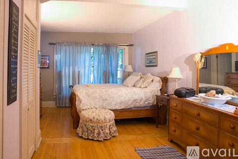 A bedroom with a bed, a dresser, and a window with curtains.