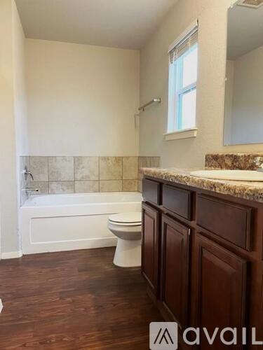 A white toilet sits in a bathroom with wooden floors and a marble counter.