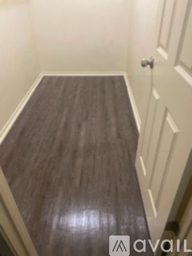 A hallway with a wooden floor and white walls.