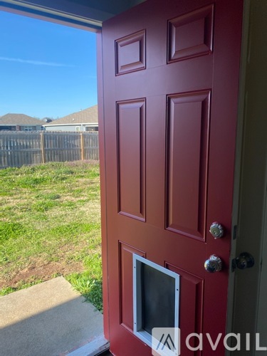A red door with a mail slot and a handle is open.