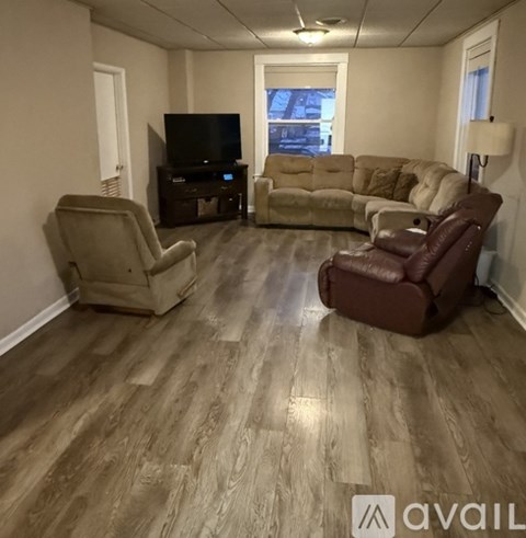 A living room with a brown leather chair and a wooden floor.
