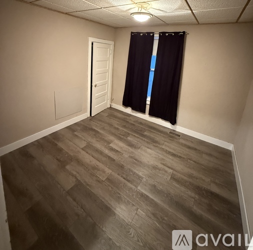 A room with wooden flooring and a white door.