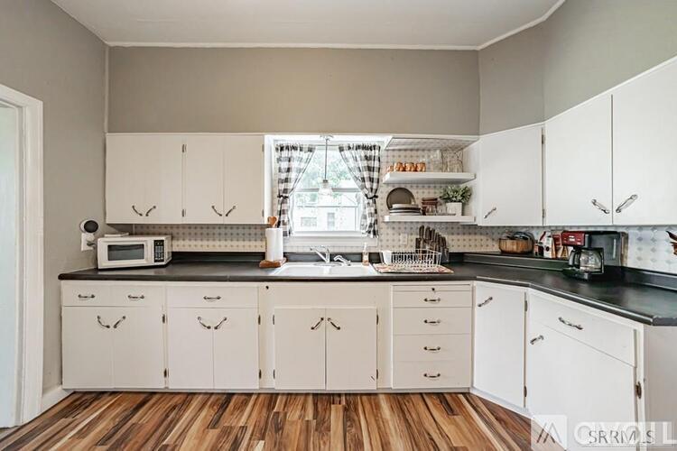 A kitchen with white cabinets and a wooden floor.