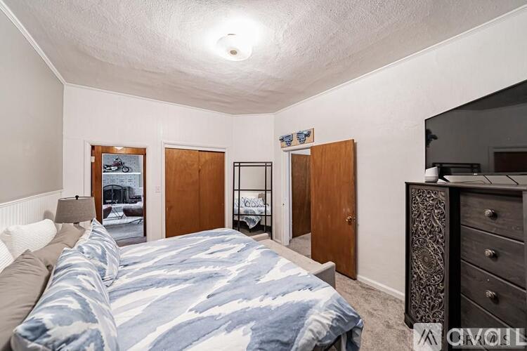 A bedroom with a bed, dresser, and a painting on the wall.