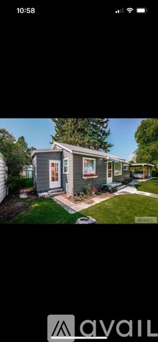 A mobile home with a front yard and a tree.