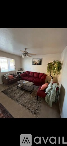 A living room with a red couch and a ceiling fan.