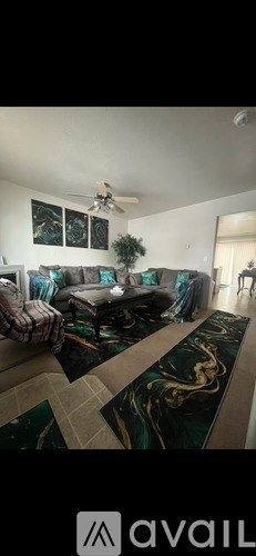A living room with a black and gold rug and a ceiling fan.