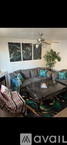 A living room with a grey couch, a coffee table, and a ceiling fan.