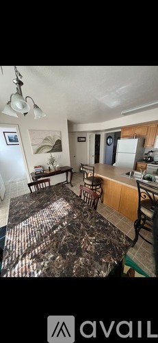 A kitchen with a table and chairs in the foreground and a refrigerator in the background.