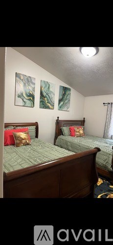Two twin beds with green bedspreads and red pillows in a room.