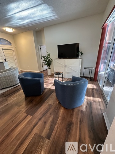 A living room with a television and two blue chairs.