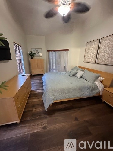 A bedroom with a bed, dresser, and ceiling fan.