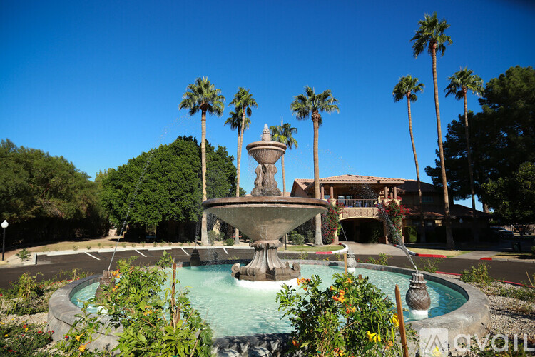 A fountain in the middle of a pool surrounded by palm trees.