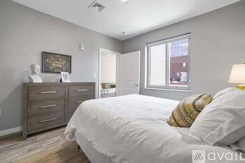 A bedroom with a bed, dresser, and a window.