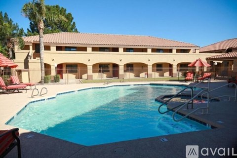 A large swimming pool in front of a building with a red umbrella.