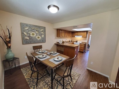 A dining room with a table set for two and a painting on the wall.