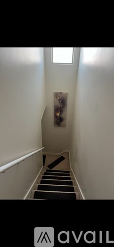 A staircase with a black railing and steps leading up to a window.