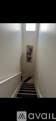 A staircase with a black railing and steps leading up to a window.