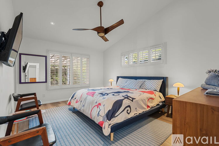 A bedroom with a bed, a ceiling fan, and a chair.