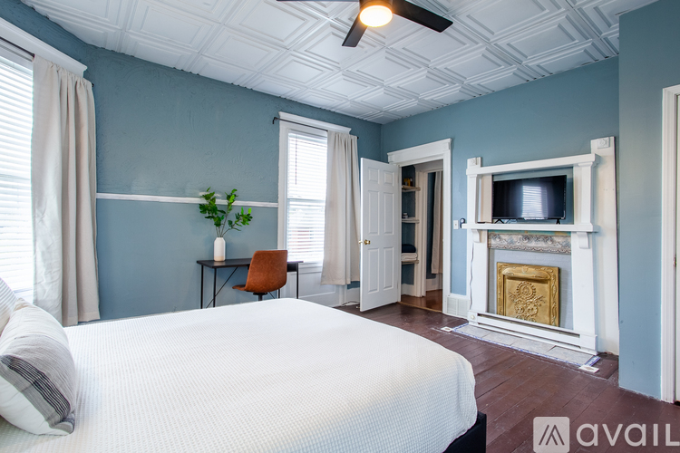 A bedroom with a bed, a chair, a plant, and a fireplace.