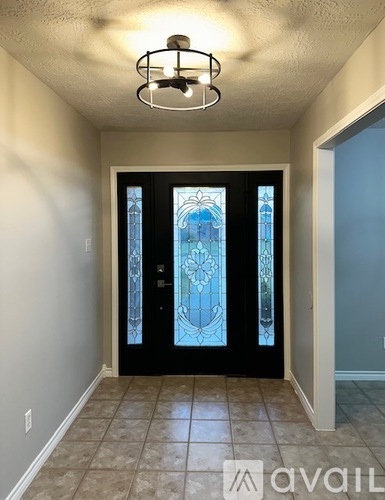 A hallway with a glass door and tiled floor.