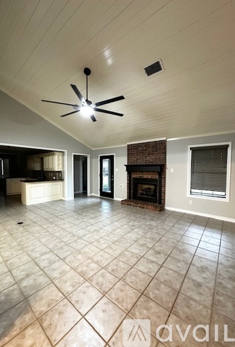 A spacious living room with a fireplace and a ceiling fan.