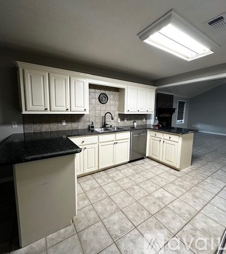 A kitchen with white cabinets and black countertops.