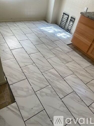 A room with white tiled flooring and a wooden cabinet.