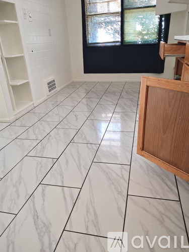A kitchen with a white tile floor and a wooden cabinet.