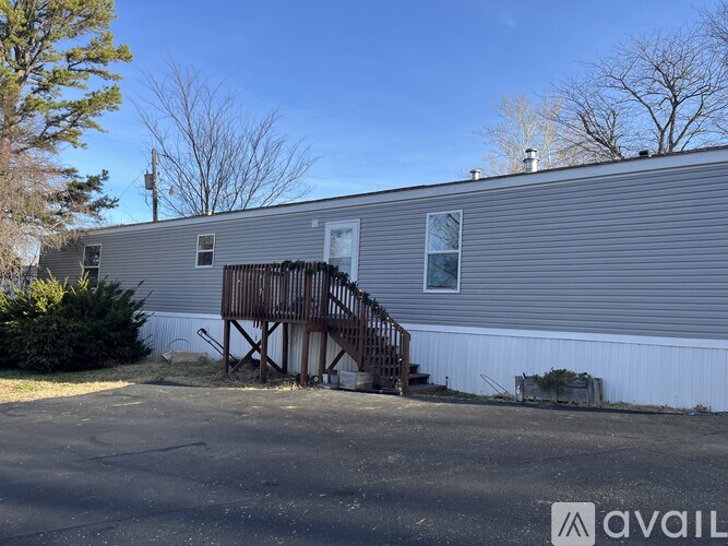A house with a grey siding and a wooden staircase leading to the front door.