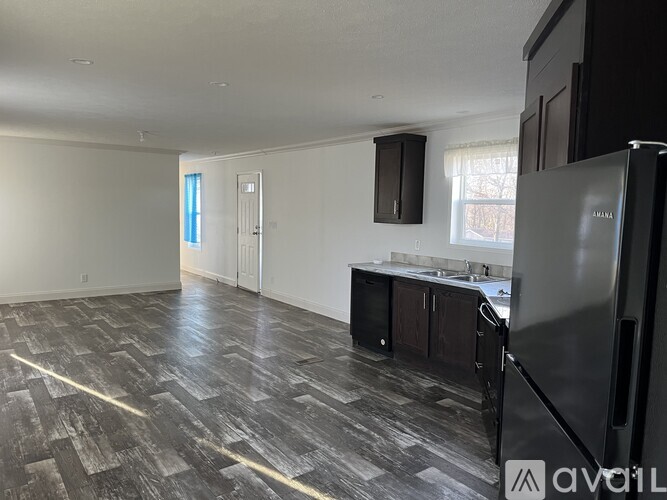 A kitchen with a black fridge and wooden flooring.