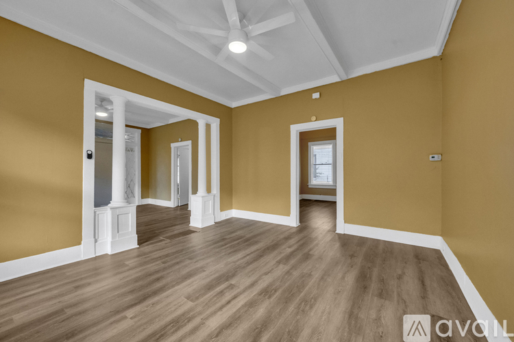 A spacious room with wooden flooring and white trim.