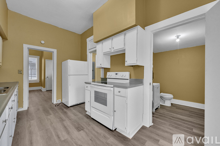 A kitchen with white appliances and cabinets in a room with wooden flooring.