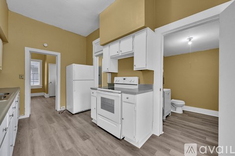 A kitchen with white appliances and cabinets in a room with wooden flooring.